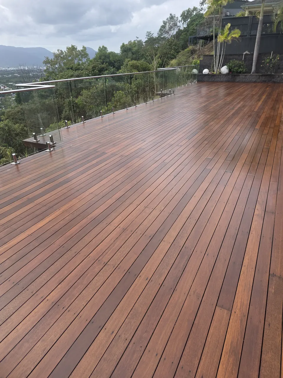 Large oiled timber deck overlooking green hills and trees