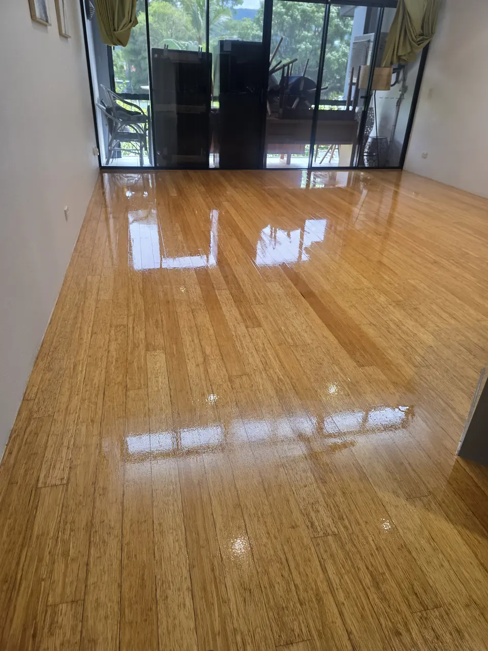 Honey-coloured glossy timber floor in a room with glass doors